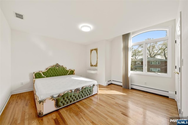 bedroom featuring baseboards, visible vents, baseboard heating, and light wood finished floors