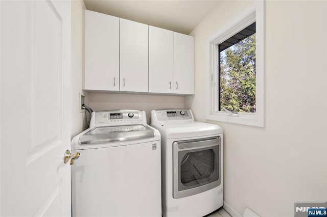 clothes washing area featuring cabinet space and washer and clothes dryer