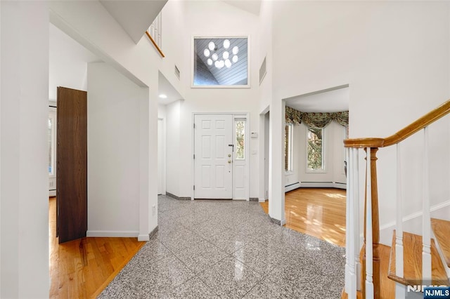 entrance foyer with a towering ceiling, granite finish floor, baseboards, a baseboard radiator, and visible vents