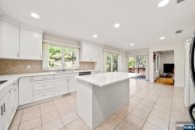 kitchen with visible vents, light countertops, light tile patterned floors, a sink, and backsplash