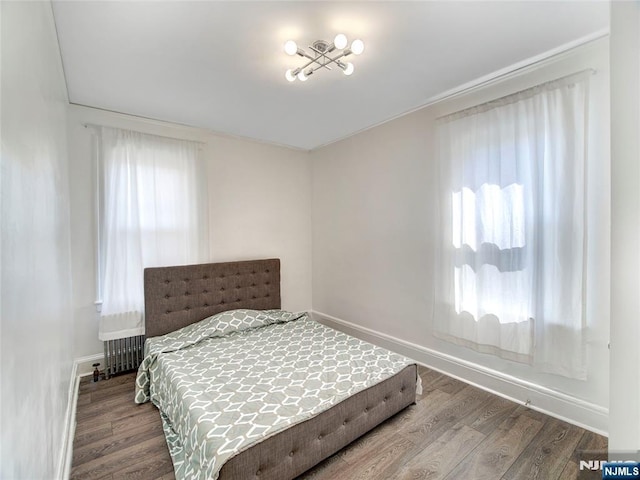 bedroom featuring radiator heating unit, wood finished floors, and baseboards