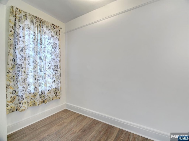 spare room featuring baseboards and wood finished floors