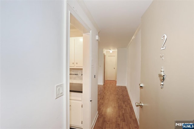 corridor featuring wood finished floors and baseboards
