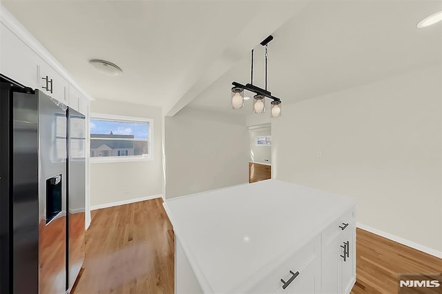 kitchen featuring baseboards, white cabinets, stainless steel refrigerator with ice dispenser, and light wood-type flooring