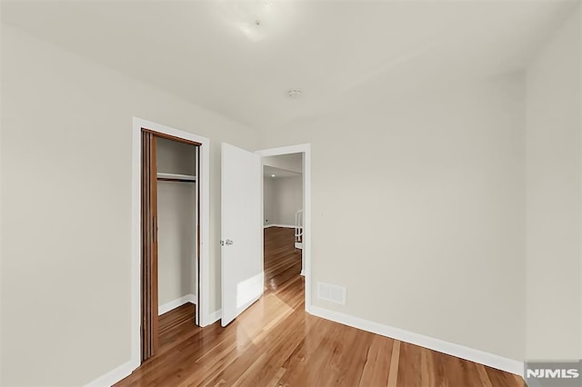 unfurnished bedroom featuring visible vents, a closet, light wood-style flooring, and baseboards
