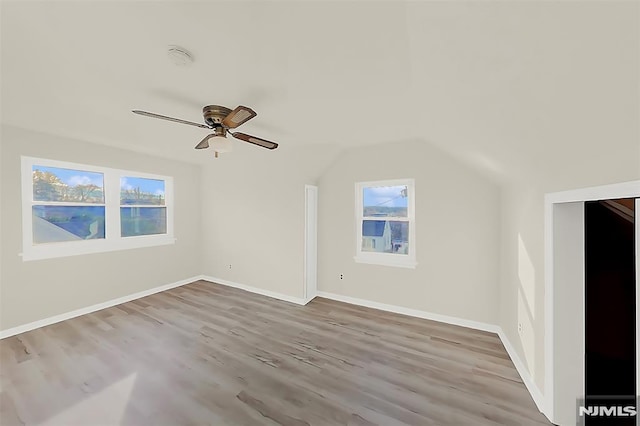 additional living space featuring a ceiling fan, a wealth of natural light, wood finished floors, and vaulted ceiling