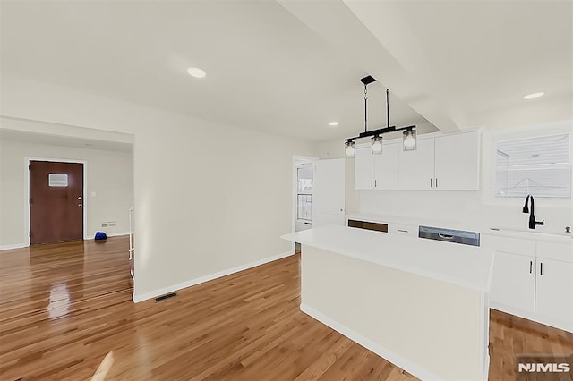 kitchen featuring baseboards, a sink, white cabinets, and light countertops