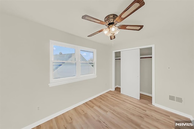 unfurnished bedroom featuring a closet, a ceiling fan, visible vents, light wood-style flooring, and baseboards