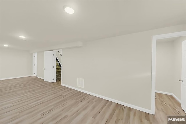 finished basement with visible vents, recessed lighting, light wood-style floors, baseboards, and stairway