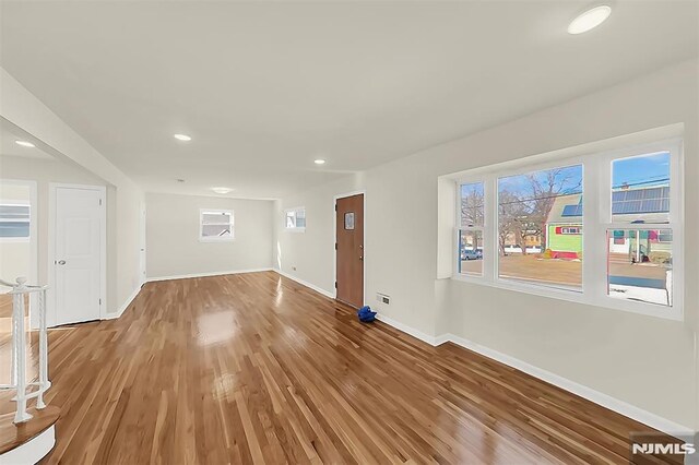 unfurnished living room with light wood-style floors, a healthy amount of sunlight, recessed lighting, and baseboards
