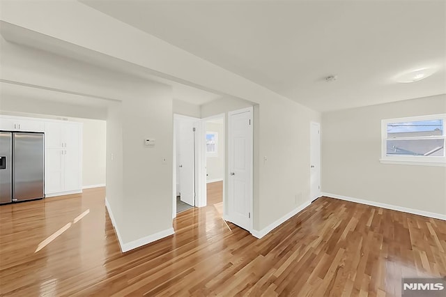 spare room featuring light wood-style floors and baseboards