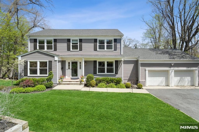 view of front of home featuring driveway, roof with shingles, a front lawn, and a garage