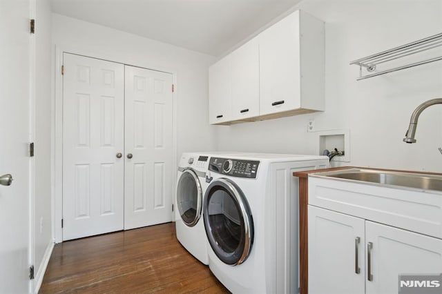 washroom with washing machine and clothes dryer, cabinet space, dark wood finished floors, and a sink