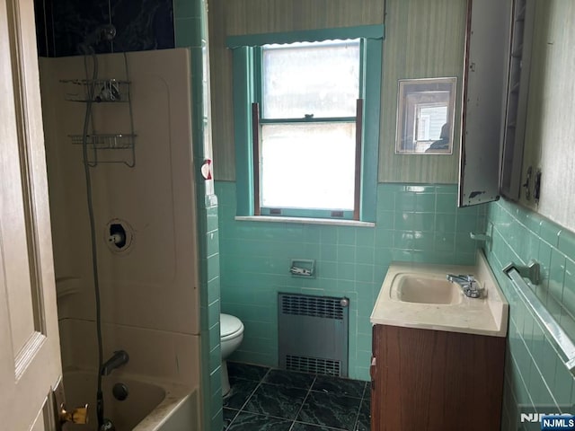 bathroom with radiator, toilet, tile walls, vanity, and  shower combination