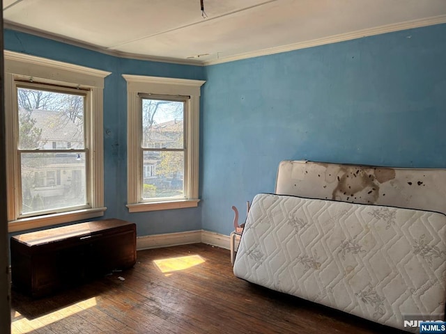 bedroom featuring wood-type flooring, ornamental molding, and baseboards