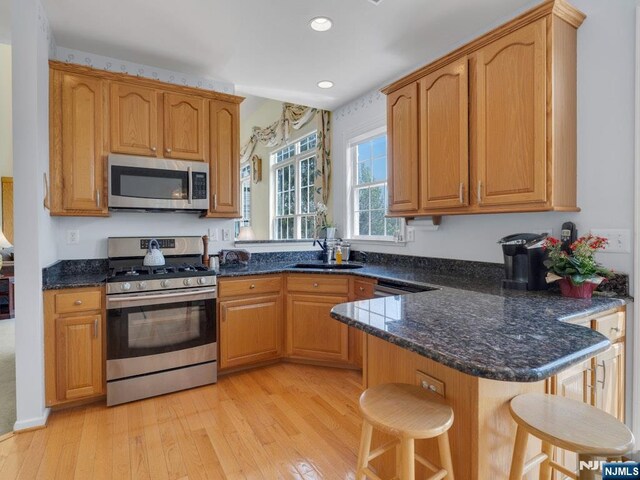 6 Knollwoods, Oakland, NJ 07436 - kitchen featuring dark stone countertops, a breakfast bar area, stainless steel appliances, and light wood-style floors