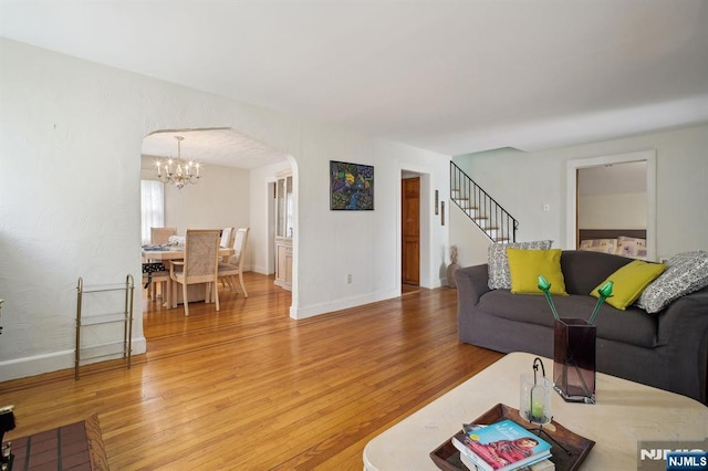884 Helen St, Teaneck, NJ 07666 - living room featuring arched walkways, light wood-type flooring, a chandelier, baseboards, and stairs