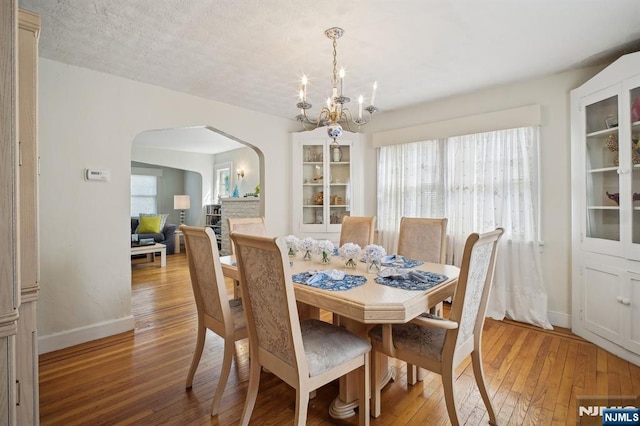 884 Helen St, Teaneck, NJ 07666 - dining area featuring arched walkways, light wood finished floors, a chandelier, and baseboards