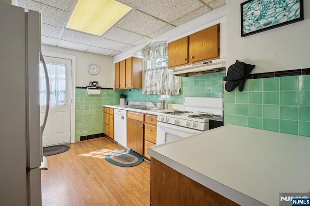 884 Helen St, Teaneck, NJ 07666 - kitchen with white appliances, under cabinet range hood, light wood-style floors, brown cabinetry, and a sink
