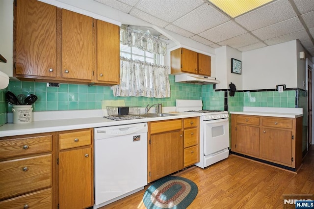 884 Helen St, Teaneck, NJ 07666 - kitchen with white appliances, under cabinet range hood, light wood-style flooring, light countertops, and brown cabinetry