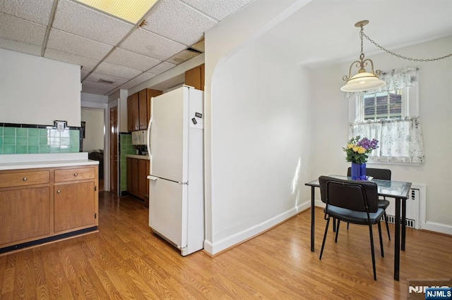 884 Helen St, Teaneck, NJ 07666 - kitchen with freestanding refrigerator, light countertops, light wood-style flooring, brown cabinets, and backsplash