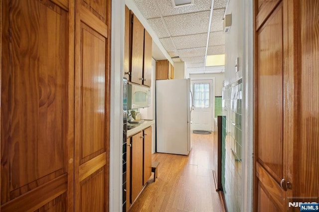884 Helen St, Teaneck, NJ 07666 - kitchen with white appliances, a drop ceiling, brown cabinets, light wood-style flooring, and light countertops
