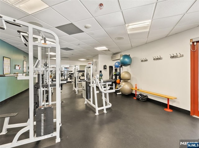 gym with a paneled ceiling and baseboards