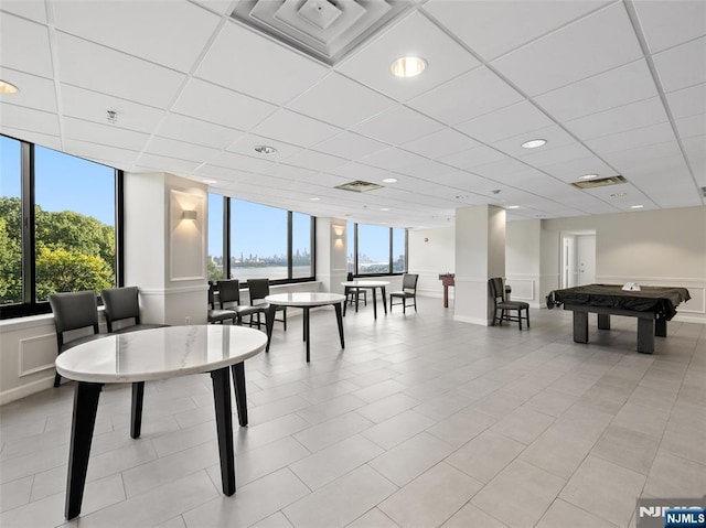 recreation room featuring visible vents, a drop ceiling, and plenty of natural light