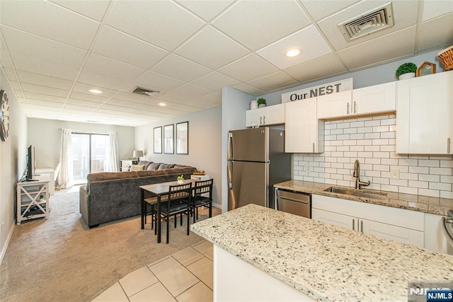 kitchen with a sink, stainless steel appliances, open floor plan, and visible vents