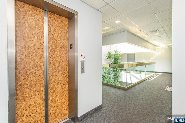 corridor featuring carpet floors, elevator, a paneled ceiling, baseboards, and visible vents