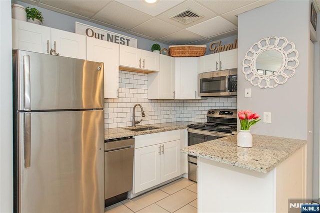 kitchen featuring visible vents, a peninsula, white cabinetry, a sink, and appliances with stainless steel finishes