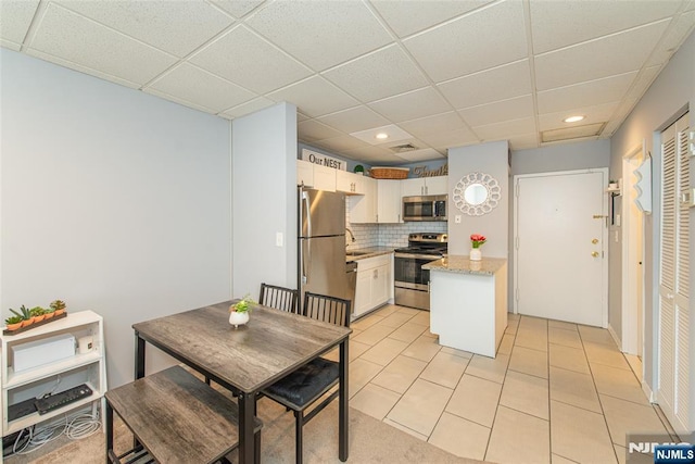 kitchen featuring decorative backsplash, a paneled ceiling, light tile patterned floors, stainless steel appliances, and recessed lighting