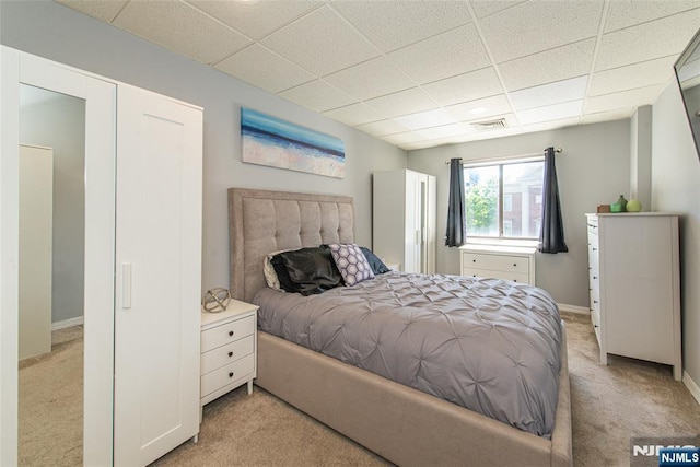 bedroom with baseboards, visible vents, a paneled ceiling, and light colored carpet
