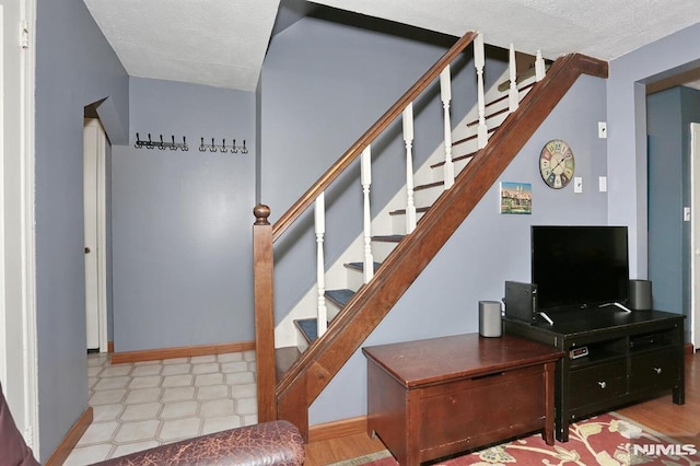 staircase featuring a textured ceiling and baseboards