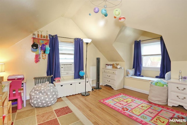 game room with radiator heating unit, light wood-style floors, and lofted ceiling