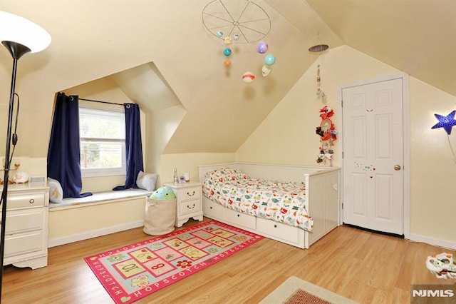 bedroom featuring baseboards, light wood finished floors, and lofted ceiling
