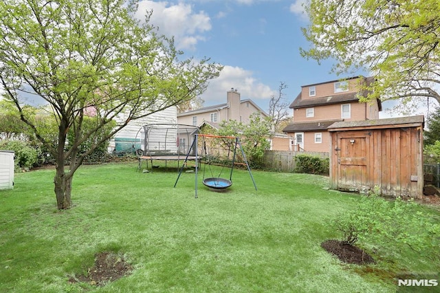 view of yard with a trampoline, an outdoor structure, a playground, a fenced backyard, and a shed