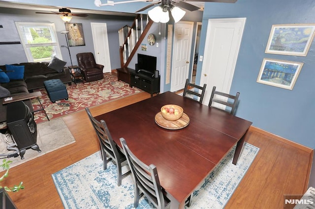 dining space featuring baseboards, a ceiling fan, wood finished floors, and stairway