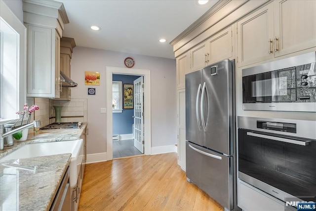 kitchen with baseboards, recessed lighting, light wood finished floors, backsplash, and stainless steel appliances