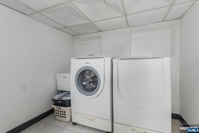 clothes washing area featuring light tile patterned floors, separate washer and dryer, baseboards, and laundry area