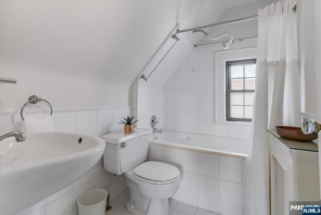 full bathroom featuring toilet, tile walls, tile patterned floors, tiled shower / bath combo, and a sink