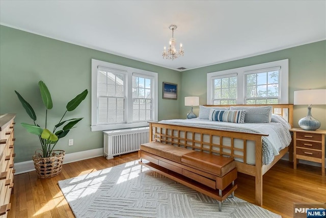 bedroom with baseboards, an inviting chandelier, wood finished floors, and radiator