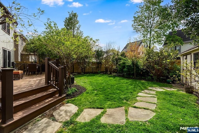 view of yard with outdoor dining area, a wooden deck, and a fenced backyard