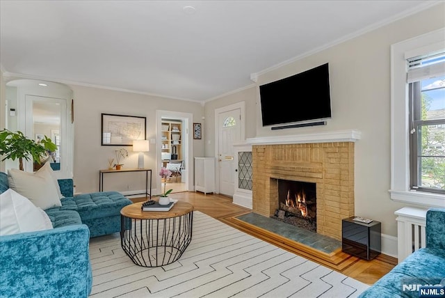 living area with a brick fireplace, baseboards, ornamental molding, and wood finished floors