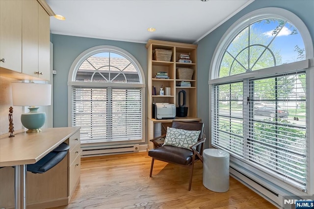 sitting room featuring crown molding, light wood finished floors, baseboard heating, and a healthy amount of sunlight
