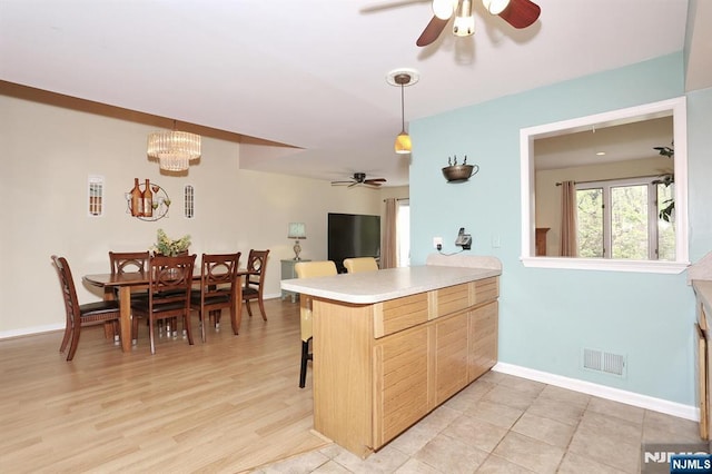 kitchen featuring pendant lighting, visible vents, light countertops, a peninsula, and ceiling fan with notable chandelier
