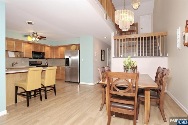 dining area featuring baseboards, light wood-style flooring, and ceiling fan with notable chandelier