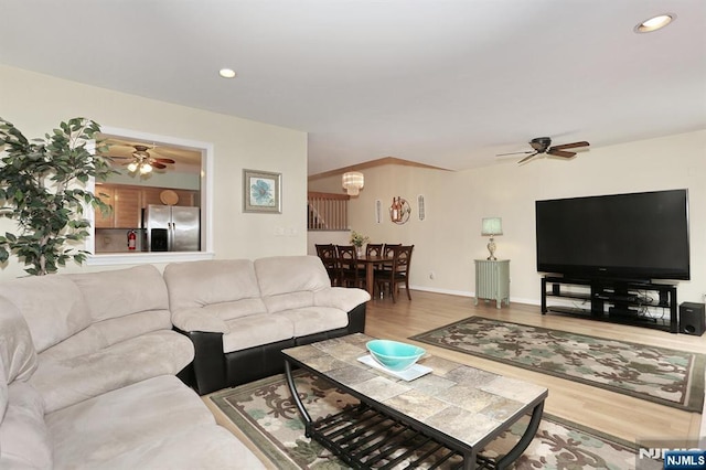 living room featuring baseboards, recessed lighting, wood finished floors, and ceiling fan with notable chandelier