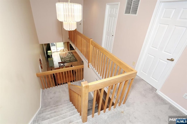 staircase with carpet flooring, visible vents, a chandelier, and baseboards