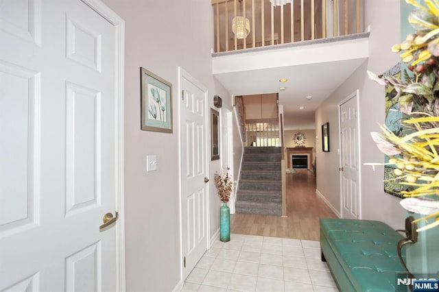 foyer featuring stairway, light tile patterned floors, a high ceiling, and baseboards